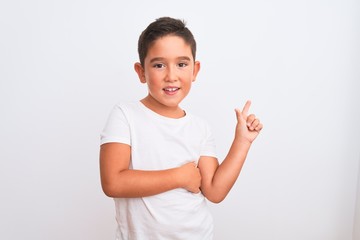 Poster - Beautiful kid boy wearing casual t-shirt standing over isolated white background with a big smile on face, pointing with hand and finger to the side looking at the camera.