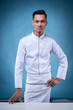 © HEMINXYLAN - A portrait of an Asian executive chef in his white uniform and apron, without his hat on blue background