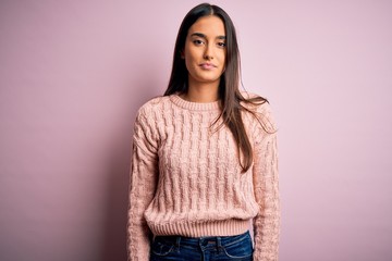 Young beautiful brunette woman wearing casual sweater over isolated pink background Relaxed with serious expression on face. Simple and natural looking at the camera.