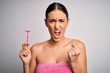 © Krakenimages.com - Young beautiful brunette woman wearing towel using razor for depilation annoyed and frustrated shouting with anger, crazy and yelling with raised hand, anger concept