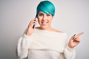 Sticker - Young woman with blue fashion hair having a conversation talking on smartphone very happy pointing with hand and finger to the side