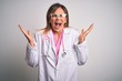 © Krakenimages.com - Middle age beautiful doctor woman wearing pink stethoscope over isolated white background celebrating mad and crazy for success with arms raised and closed eyes screaming excited. Winner concept