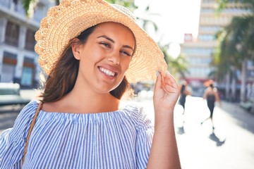 Wall Mural - Young beautiful woman smiling happy walking on city streets on a sunny day of summer