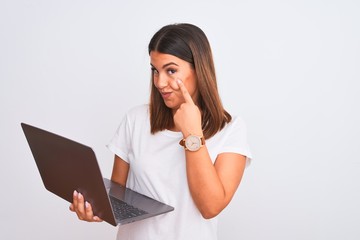 Poster - Beautiful young woman working using computer laptop over white background Pointing to the eye watching you gesture, suspicious expression