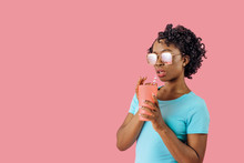 Studio Portrait Of A Cool Young Woman With Sunglasses,  Drinking From Glass With Straw