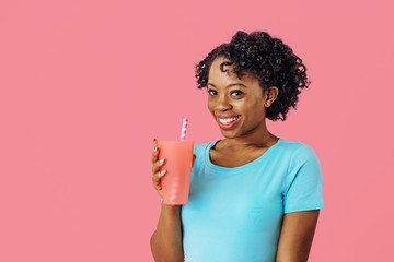 Wall Mural - Close up portrait of a happy young smiling woman  holding a drinking cup with straw and looking at camera