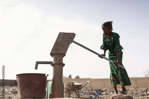 Plakat Young West Africa Woman Carrying Natural Water in a village