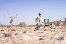 Little African Woman Transporting Fresh Water As A Drought Symbol
