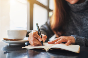 Wall Mural - Closeup image of a woman writing on a blank notebook on the table