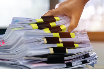 Wall Mural - Businessman hands working in stacks documents of paper files, searching information on desk office, Accounting budget report file, check working for arranging unfinished of paperwork on busy office