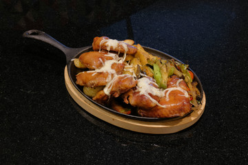 Grilled meat served in a pan on a black background.