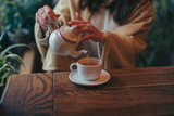 Female hands pouring tea into cup