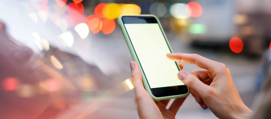 Closeup photo of female hands holding modern smartphone with blank screen. Mockup ready for text message or content. Woman's hands with cellphone. Empty display. Night street, bokeh light