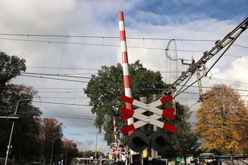 red and white barrier and cross at railroad crossing in town 't harde in the netherlands