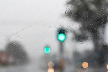 Heavy torrential rain hits the city. Traffic lights are barely seen through the windscreen.
