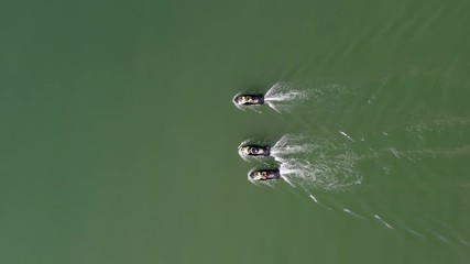Wall Mural - Three Jet skis cruising slowly in formation, Top down aerial view.