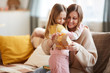 © Seventyfour - Warm-toned portrait of cute girl hugging mom after giving gift for Birthday or Mothers day, copy space