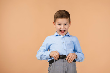 Wall Mural - satisfied little child boy looking to camera on beige background. Human emotions and facial expression. copy space