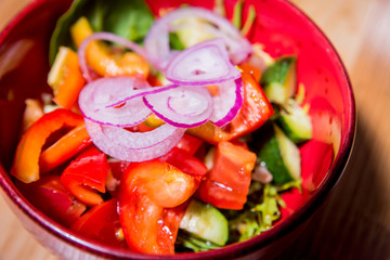 Wall Mural - Fresh vegetable salad in red plate on the wooden table. Restaurant.