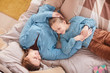 © Seventyfour - Top view portrait of happy mother hugging cute girl and smiling at each other while lying on bed at home, copy space