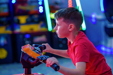 Wall Mural - Technology, gaming, entertainment and people concept - happy smiling boy in red t-shirt with playing car racing video game and steering wheel.