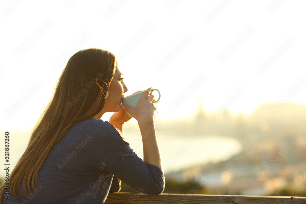 Girl drinking coffee contemplating views at sunset - obrazy, fototapety, plakaty 