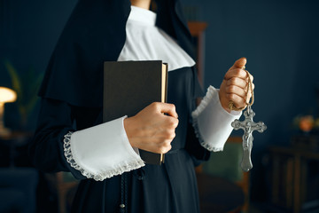 Young nun in a cassock holds book