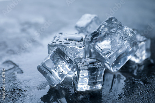 Cuadros en Lienzo Crystal clear ice cubes with water drops on grey table, closeup