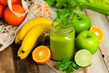 Green delicious smoothie made with apple, celery, lime, banana. Healthy eating, food and vegetarian diet concept. Antioxidant detox beverage. Clean organic ingerdients. Close up, wooden background.