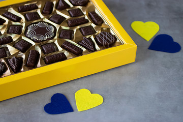 Box of chocolates and two  decorative hearts on gray background. Valentines day concept.