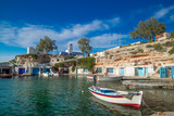 Fototapeta  - Mandrakia traditional fishing village with syrmata. Orthodox church and boat garages on Aegean sea, Milos island. Mediterranean plants and greek architecture. Greece paradise vacation