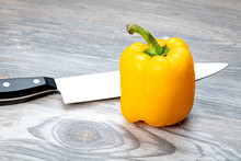 Sharp Knife Ready To Cut Into A Yellow Bell Pepper