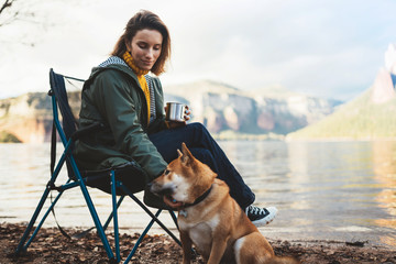 tourist traveler drink tea girl relax together dog on mountain landscape,  woman hug pet rest on lake shore nature trip