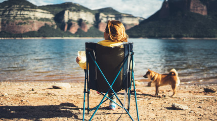 Wall Mural - happy tourist traveler sits on lake, girl hiker enjoying mountains with pet dog, breathing of fresh air in trip in spain, relax holiday, journey leisure weekend