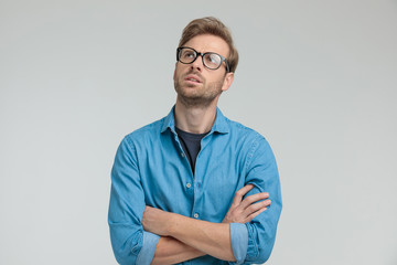 Wall Mural - confused young casual man looking up and thinking