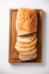 Wall Mural - Ciabatta bread cutting on a wooden board on light grey background. Top view.