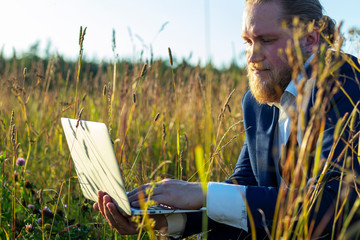 Caucasian man with laptop on the nature. Concept businessman in nature