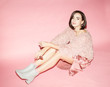 © Sergey Chumakov - woman fashion model in pink sunglasses, sweater and skirt sitting on pink background