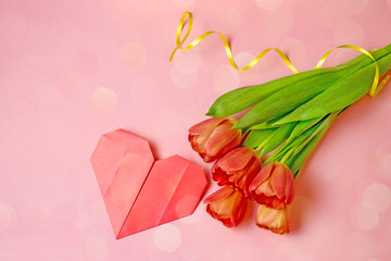 Canvas Print - Holiday card with a red bouquet of tulips and a paper heart. Bouquet of tulips on a pink background. Top view, copy space, bokeh effect