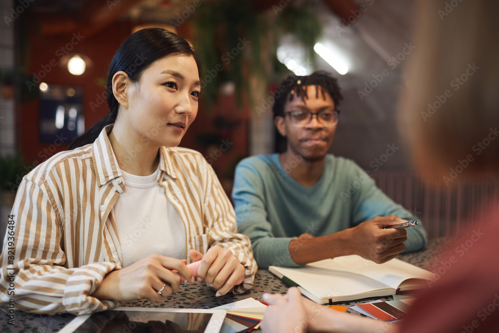 Multi-ethnic group of three business people working on project while sitting at table in cafe, copy space - obrazy, fototapety, plakaty 