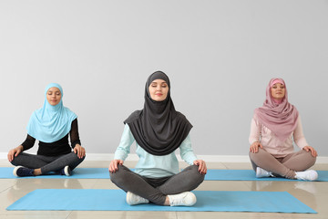 Wall Mural - Sporty Muslim women practicing yoga in gym