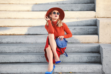 Wall Mural - Portrait of fashionable young woman sitting on steps outdoors