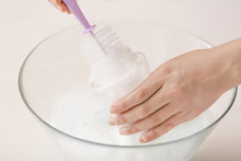 Woman Cleaning Baby Bottle At Home, Closeup