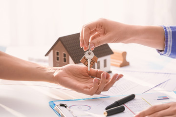 Real estate agent giving a key from new house to client in office