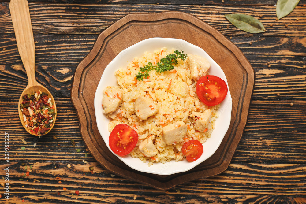 Bowl with tasty rice and chicken on table