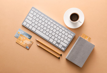 Wall Mural - Credit cards with computer keyboard, cup of coffee and stationery on color background. Concept of online banking