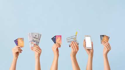 Poster - Female hands with money, credit cards, shopping cart and mobile phone on color background. Concept of online banking