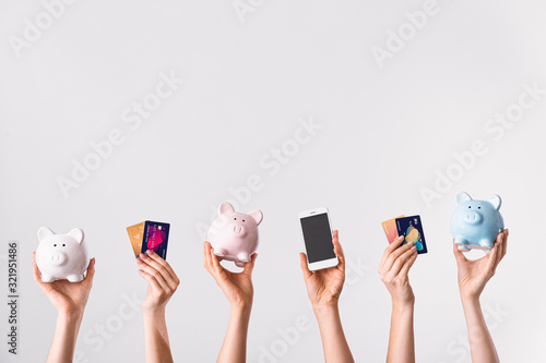 Female hands with credit cards, piggy banks and mobile phone on light background Tableau sur Toile