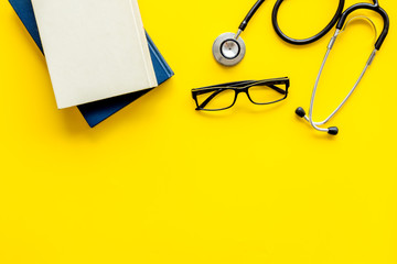 Wall Mural - Medical books near stethoscope on yellow background top-down copy space