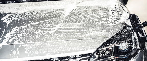 Poster - Manual car wash with white soap, foam on the body. Washing Car Using High Pressure Water.